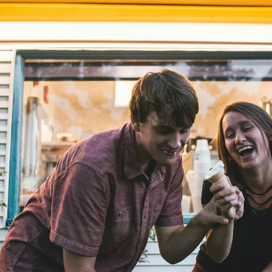 A man and a woman laughing over ice cream