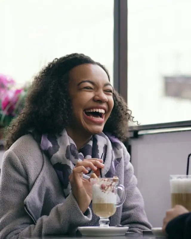 Two women laughing together at a cafe table