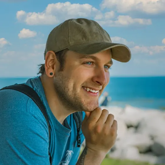 A smiling man in a cap on the coast