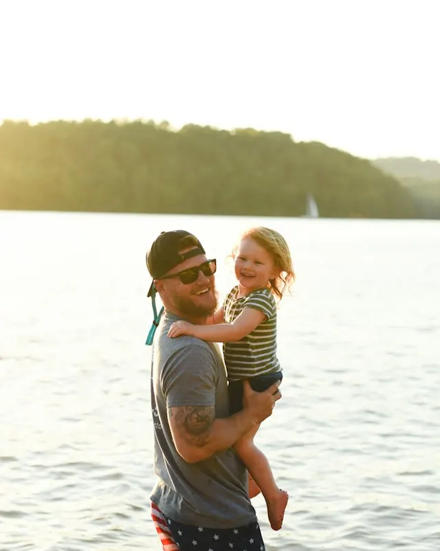 A dad holding his young daughter in the sea